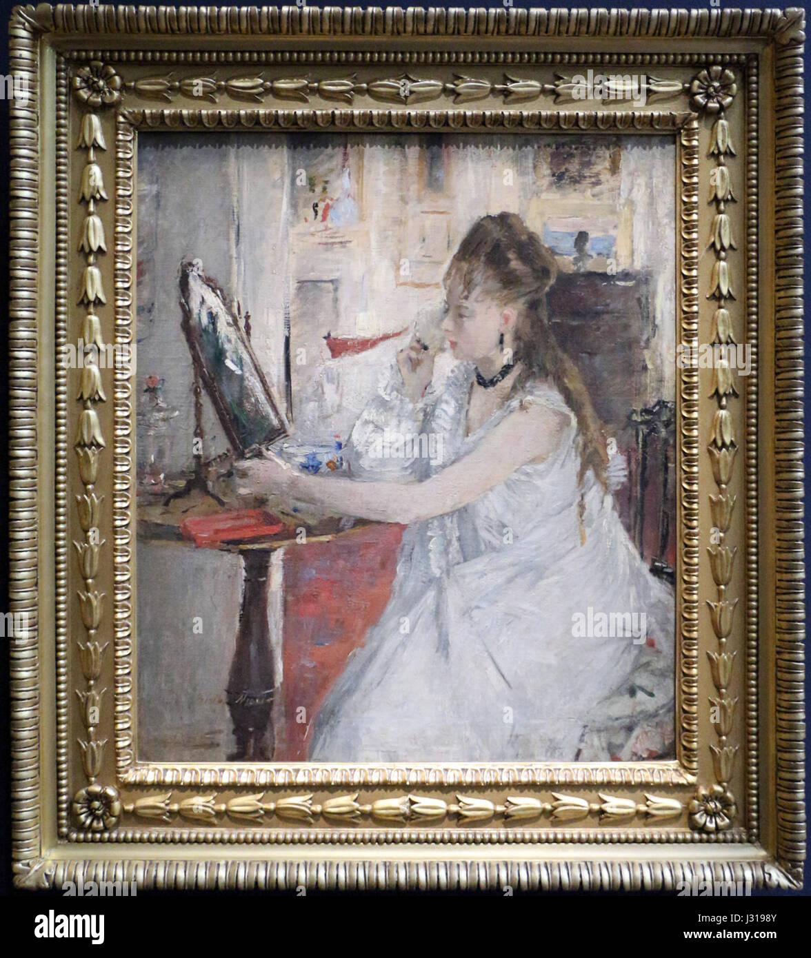 Une peinture de Berthe Morisot intitulée 'Giovane Donna Che si Impomata' (femme aux toilettes), créée en 1877. La peinture représente un moment intime et quotidien d'une femme qui se prépare, illustrant la maîtrise de l'impressionnisme par Morisot et son accent sur la subjectivité féminine. Banque D'Images