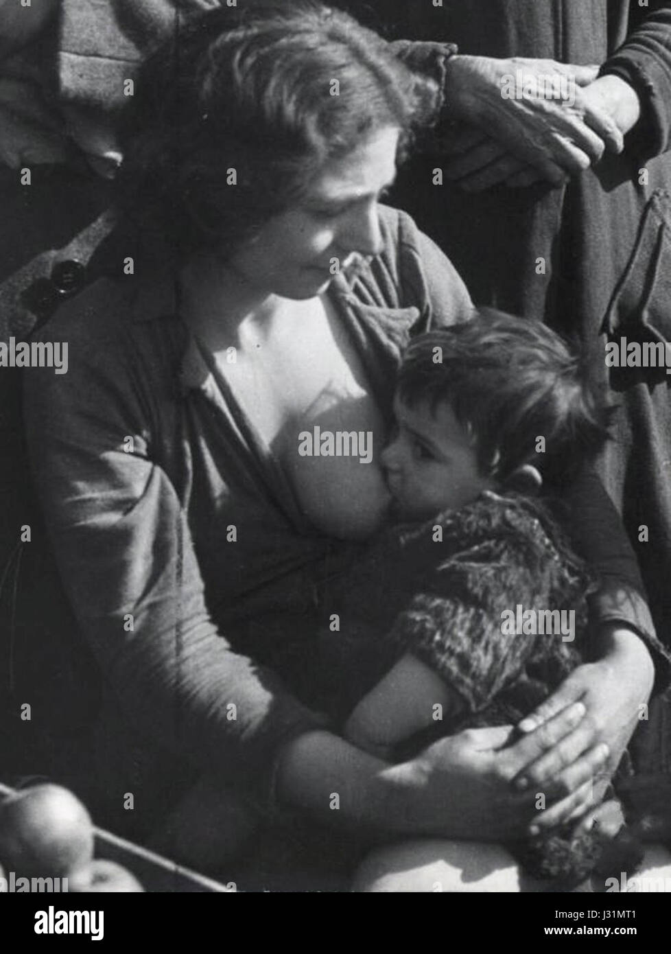 Cette image capture une femme italienne allaitant son enfant à Naples en 1944, une période importante pendant la seconde Guerre mondiale, lorsque l'Italie était sous occupation de l'axe et faisait face à des défis en temps de guerre. Banque D'Images