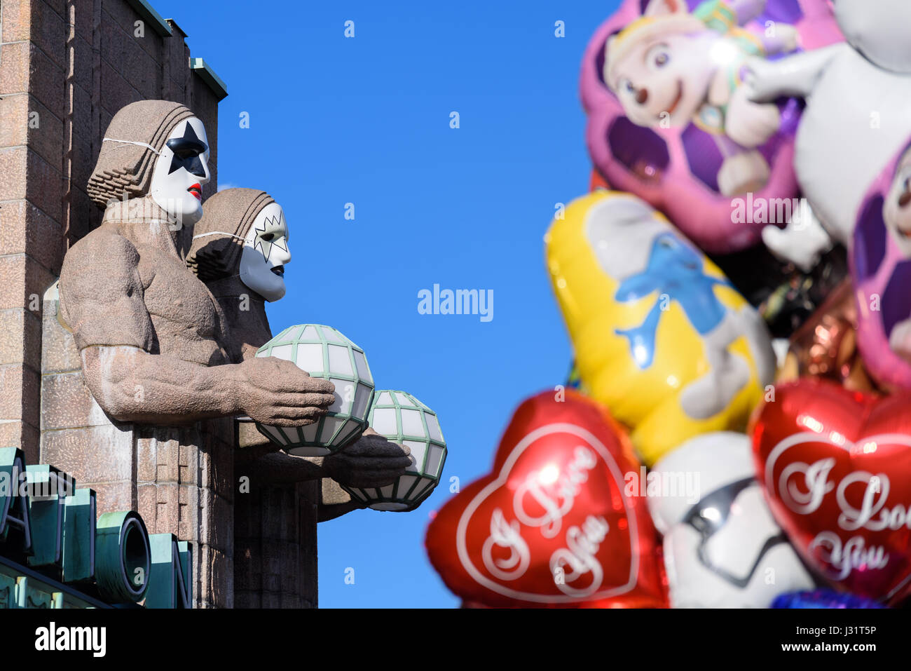 Helsinki, Finlande. 1er mai 2017. Pierre emblématique des statues d'hommes par le côté de l'entrée de la Gare Centrale d'Helsinki décorée comme porter des masques groupe Kiss pendant Premier Mai célébrations dans Helsinki, Finlande avec des ballons colorés sur l'avant-plan. Credit : Mikko Palonkorpi / Alamy Live News Crédit : Jekurantodistaja/Alamy Live News Banque D'Images