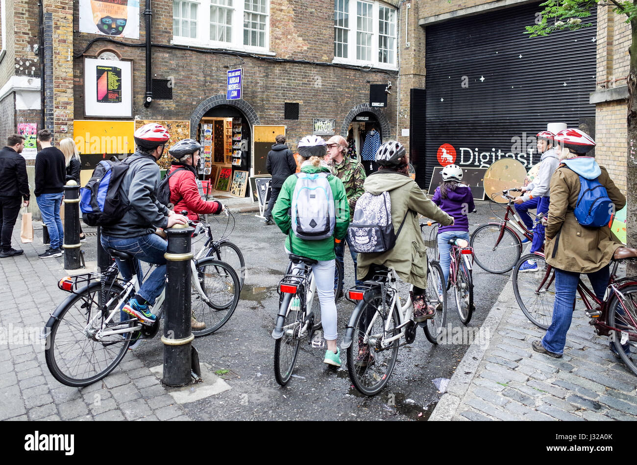 Les touristes sur un tour à vélo de Londres énumérés à leur guide de Londres de Brick Lane, une destination touristique populaire dans l'Est de Londres. Banque D'Images