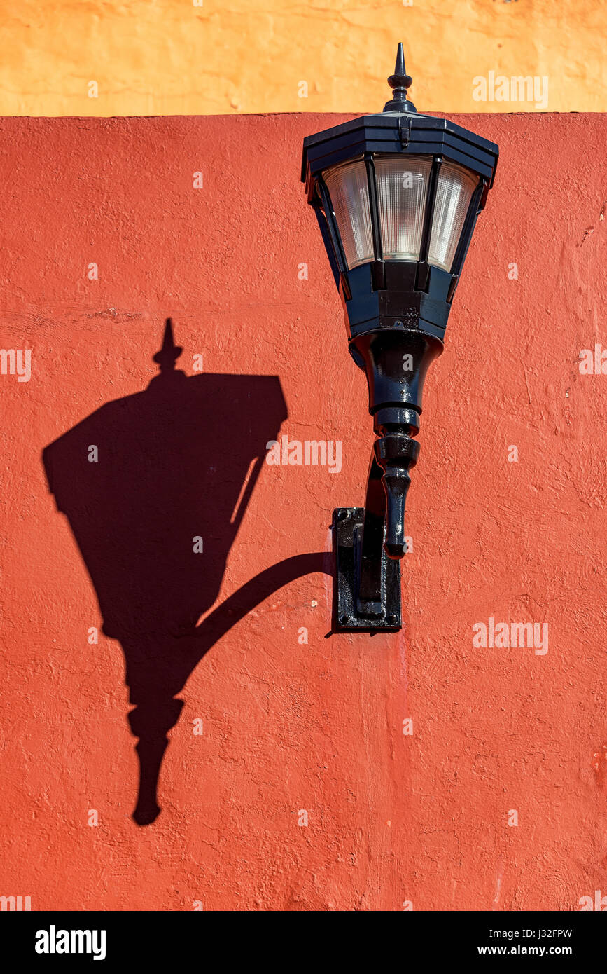 La rue noire de lumière sur un mur rouge jette une ombre forte à Campeche, Mexique Banque D'Images