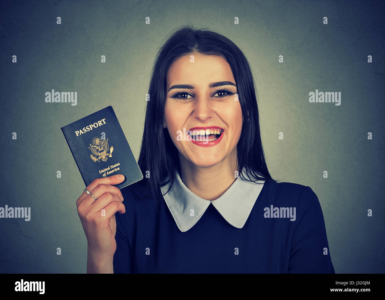 Portrait séduisant jeune femme excité avec passeport USA isolé sur fond de mur gris. Des émotions positives face à l'expression. Trave d'immigration Banque D'Images