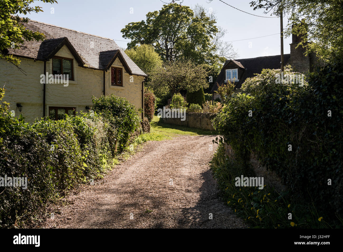 Un cottage en pierre / maison avec murs rendus dans la campagne anglaise sur une journée ensoleillée. Allée en gravier. Scène pittoresque typiquement anglais. Banque D'Images