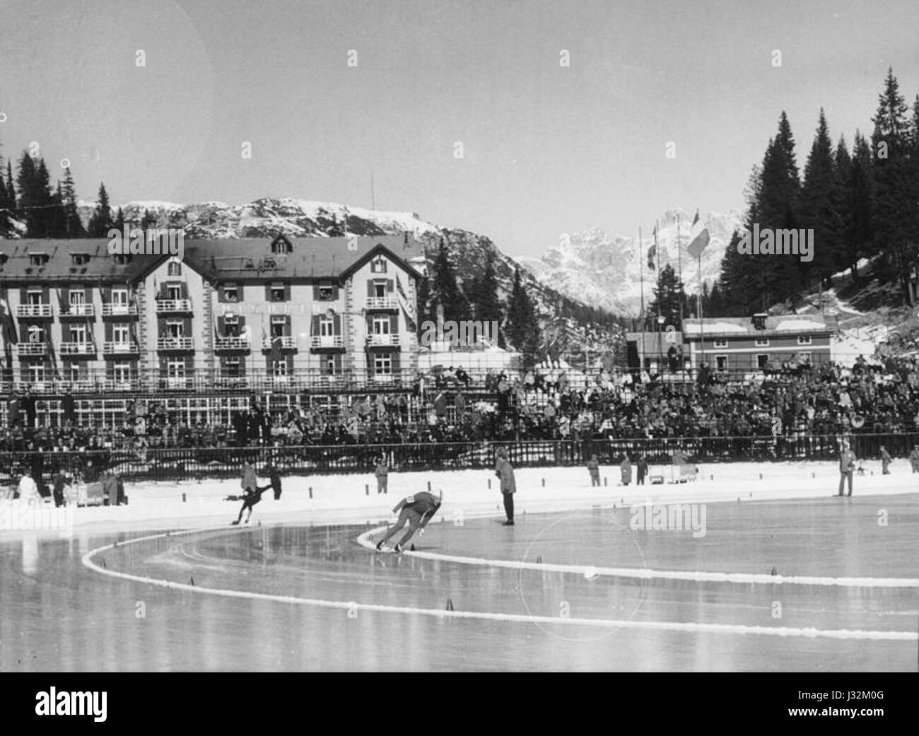 L'image intitulée 'Pista di pattinaggio a Misurina' capture une scène hivernale d'une patinoire à Misurina, près de Cortina, en 1956. La scène présente des individus patinant sur des lacs gelés au milieu des Alpes italiennes enneigées, représentant la culture des sports d'hiver de l'Italie du milieu du XXe siècle. Banque D'Images