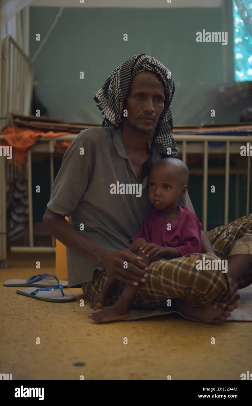 Un enfant mal nourri est assis sur les genoux de son père à l'hôpital Banadir de Mogadiscio, en Somalie, le 9 mars 2017. La Somalie connaît actuellement une grave sécheresse, et peut être au bord de la famine, à moins que l'action humanitaire d'urgence est prise rapidement. L'AMISOM Photo/Tobin Jones Banque D'Images