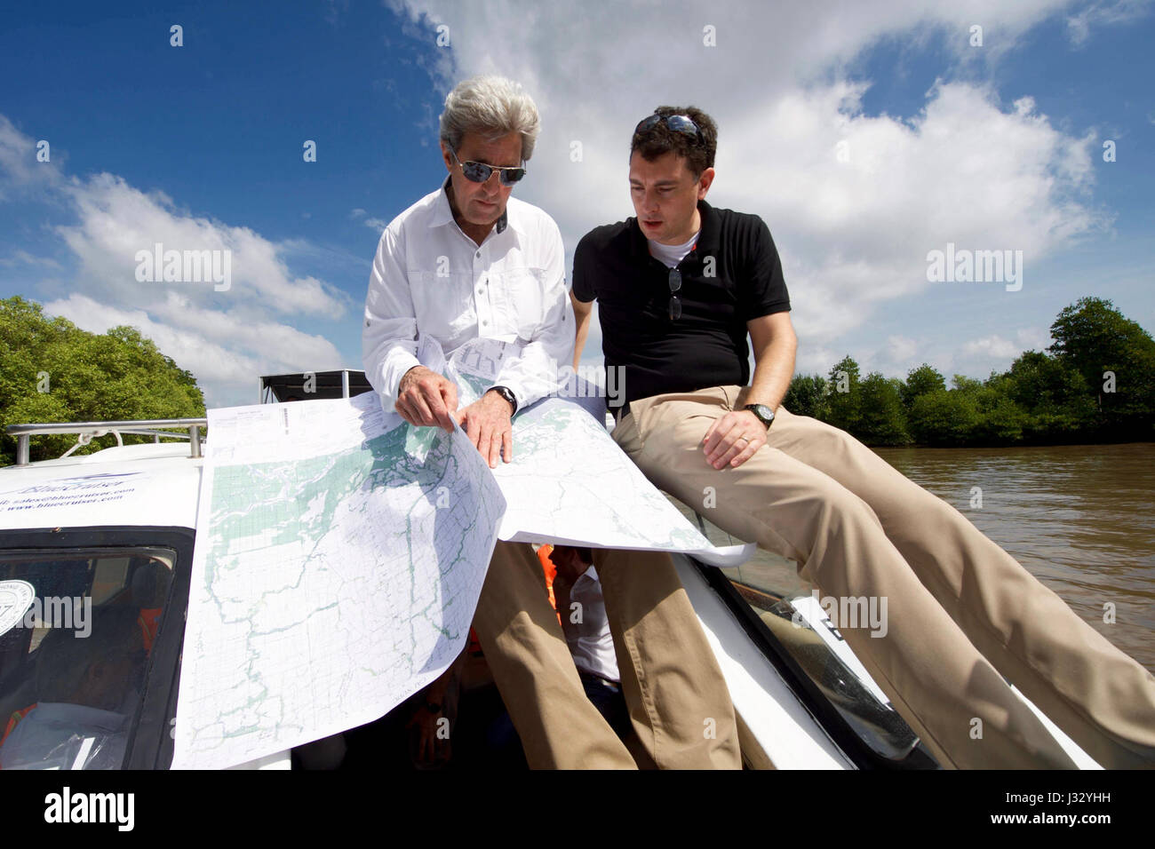 Le secrétaire d'État américain John Kerry et le professeur Edward Miller examinent les cartes de la rivière Bay Hap, au Vietnam, pour revisiter le site d'une bataille de 1969 où Kerry a remporté l'étoile d'argent. La visite est axée sur les efforts de réconciliation et de restauration de l'environnement dans le delta du Mékong. Banque D'Images