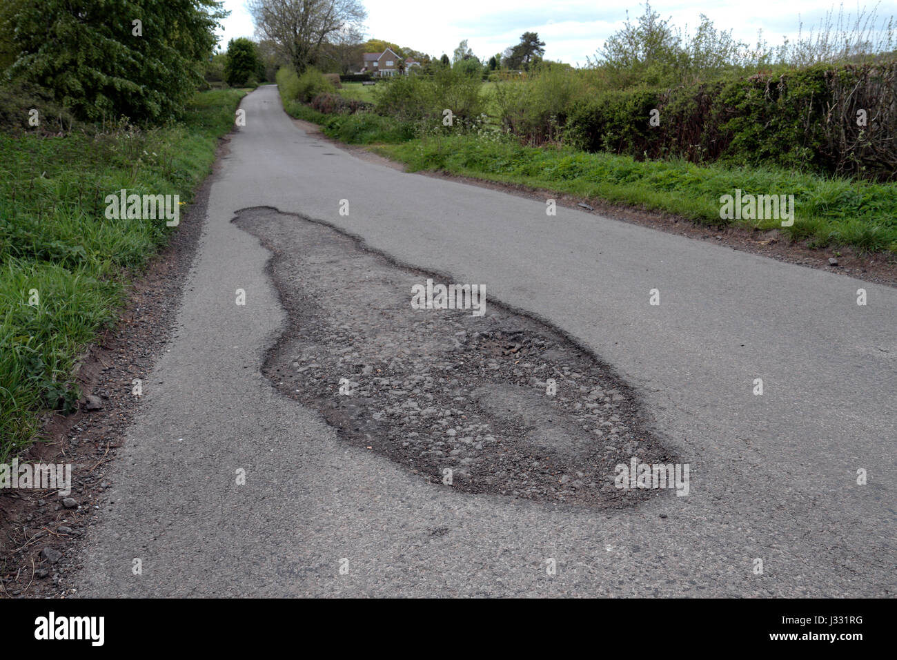 Un grand pot trou sur une route de campagne en Angleterre. Banque D'Images