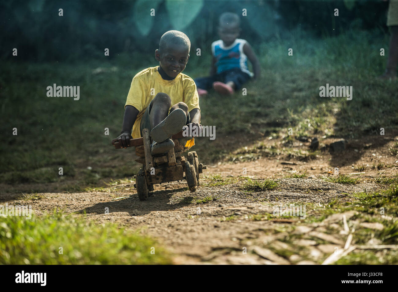 Petit garçon à cheval sur un simple véhicule jouet en bois, Sao Tomé, Sao Tomé et Principe, Afrique Banque D'Images