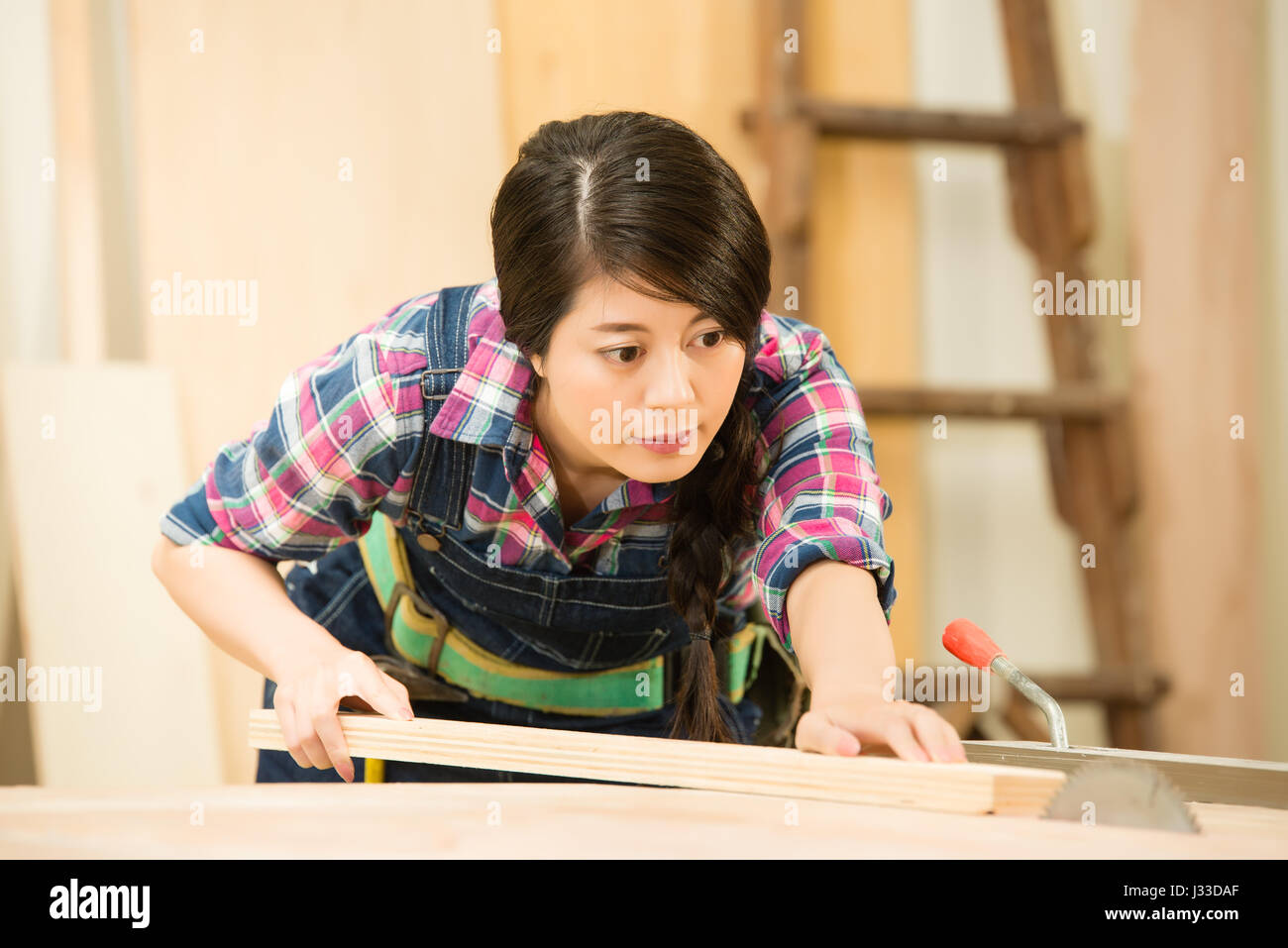 Menuisier de couper un morceau de bois dans son atelier de menuiserie, à l'aide d'une scie circulaire. race mixte modèle chinois asiatique. Banque D'Images