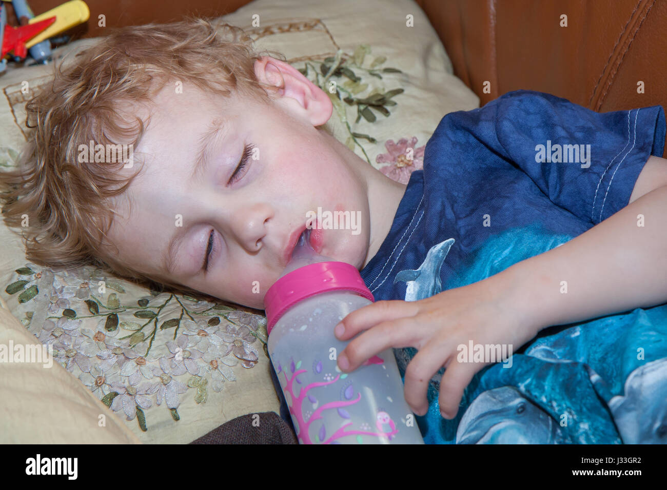 Un petit enfant dormir avec un biberon de lait Banque D'Images