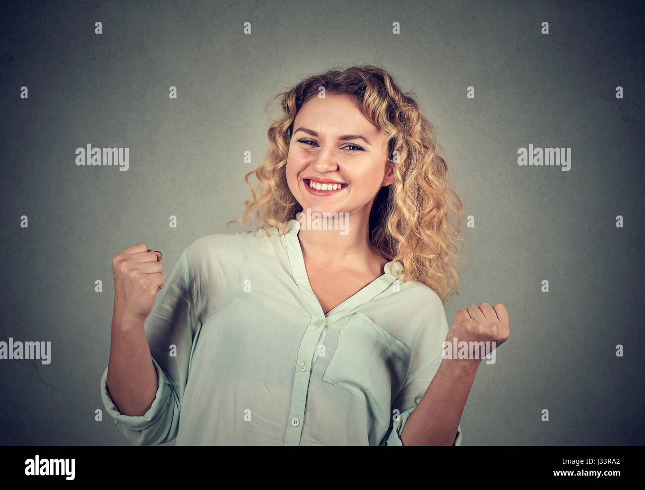 Closeup portrait heureux femme réussie des poings de pompage Célébrons les succès isolé sur fond de mur gris. L'expression faciale des émotions humaines positives Banque D'Images