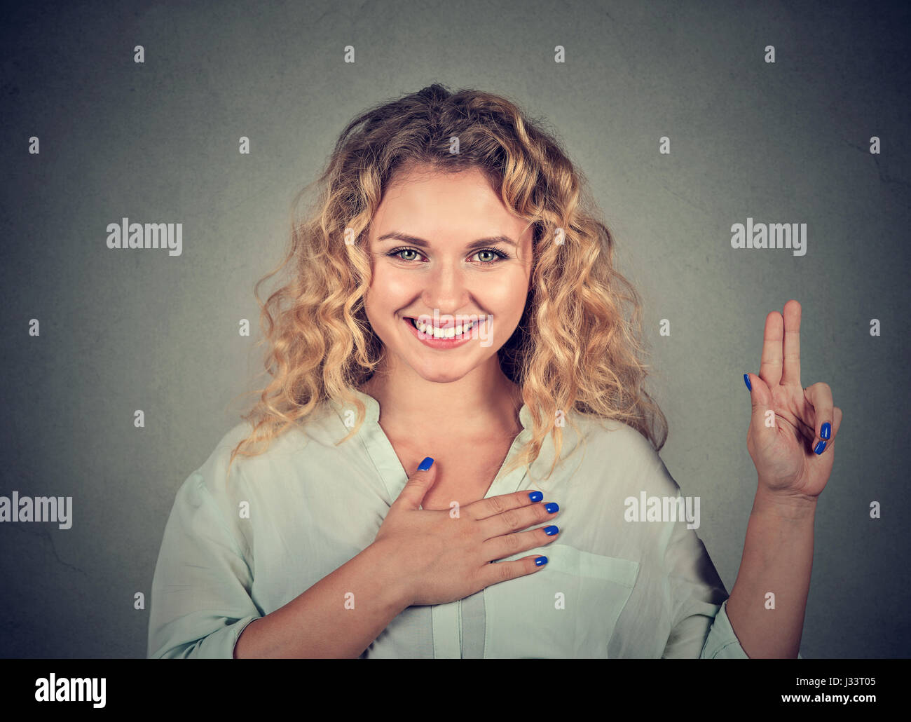Jeune femme heureuse dans les verres faire une promesse isolé sur fond de mur gris Banque D'Images