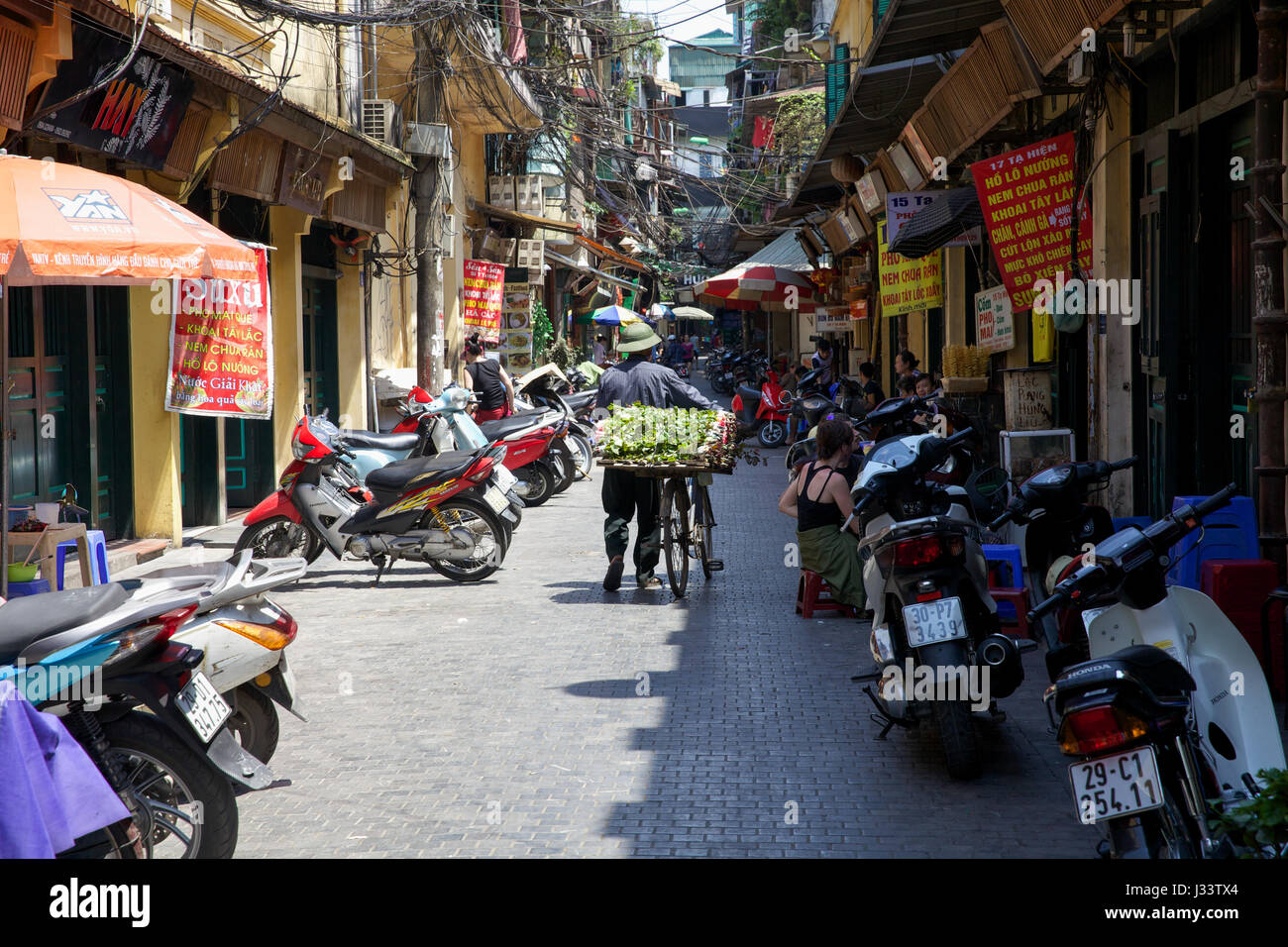 HANOI, VIETNAM - MAI 10 Vietnamiens : vendeuse de fleurs dans la rue de Hanoi avec son vélo le 10 mai 2014 à Hanoi, Vietnam. Banque D'Images