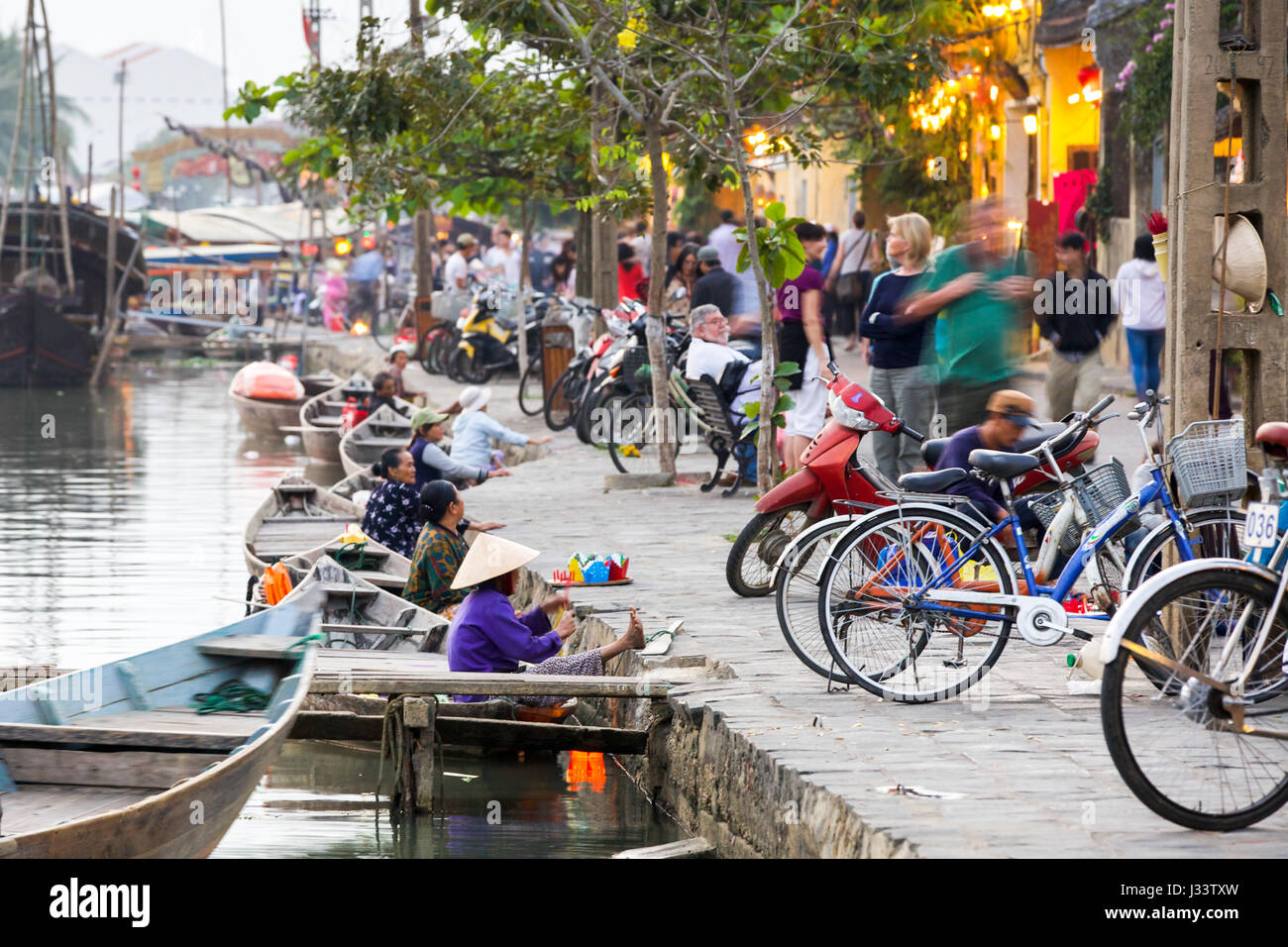 HOI AN, VIETNAM - 15 mars 2014 : vieilles femmes vendent des bateaux lanters colorés sur la rue de l'ancienne ville de Hoi An avec une longue exposition effi Banque D'Images