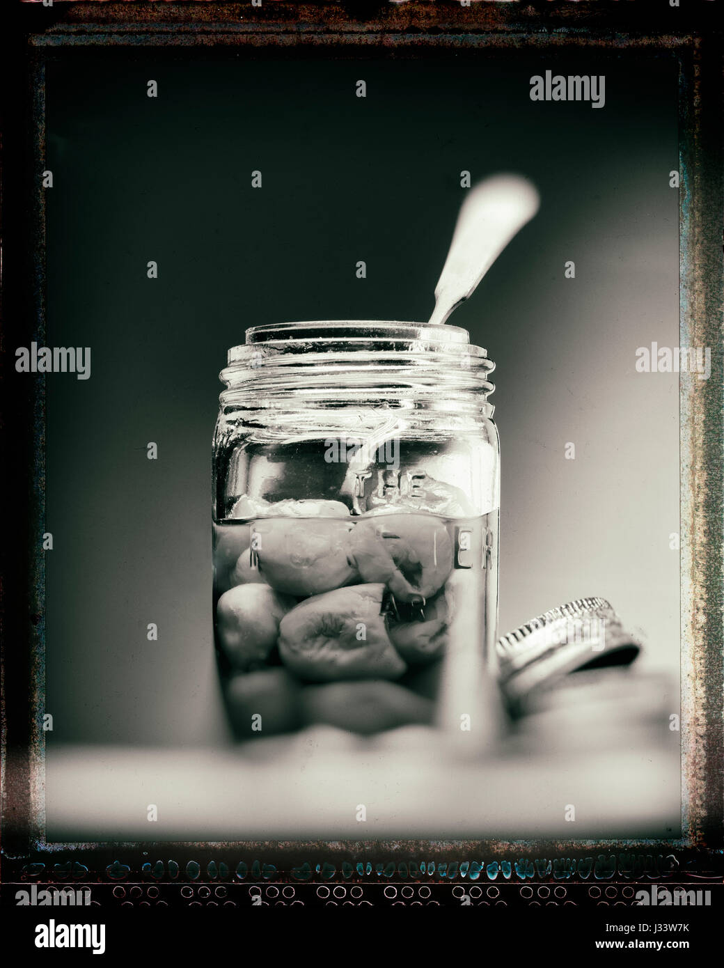 Les poivrons dans un bocal en verre avec une cuillère Banque D'Images