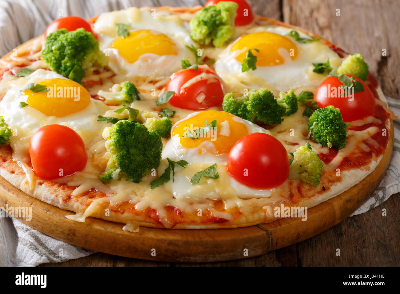 Petit-déjeuner copieux de pizza avec des œufs, le brocoli, les tomates et le persil libre sur la table horizontale. Banque D'Images