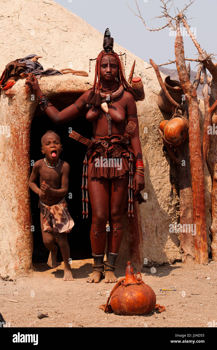 Femme Himba debout devant sa hutte près de Epupa Falls. Peuple Himba vit dans la région de Kunene, le nord de la Namibie dans la frontière de l'Angola Banque D'Images