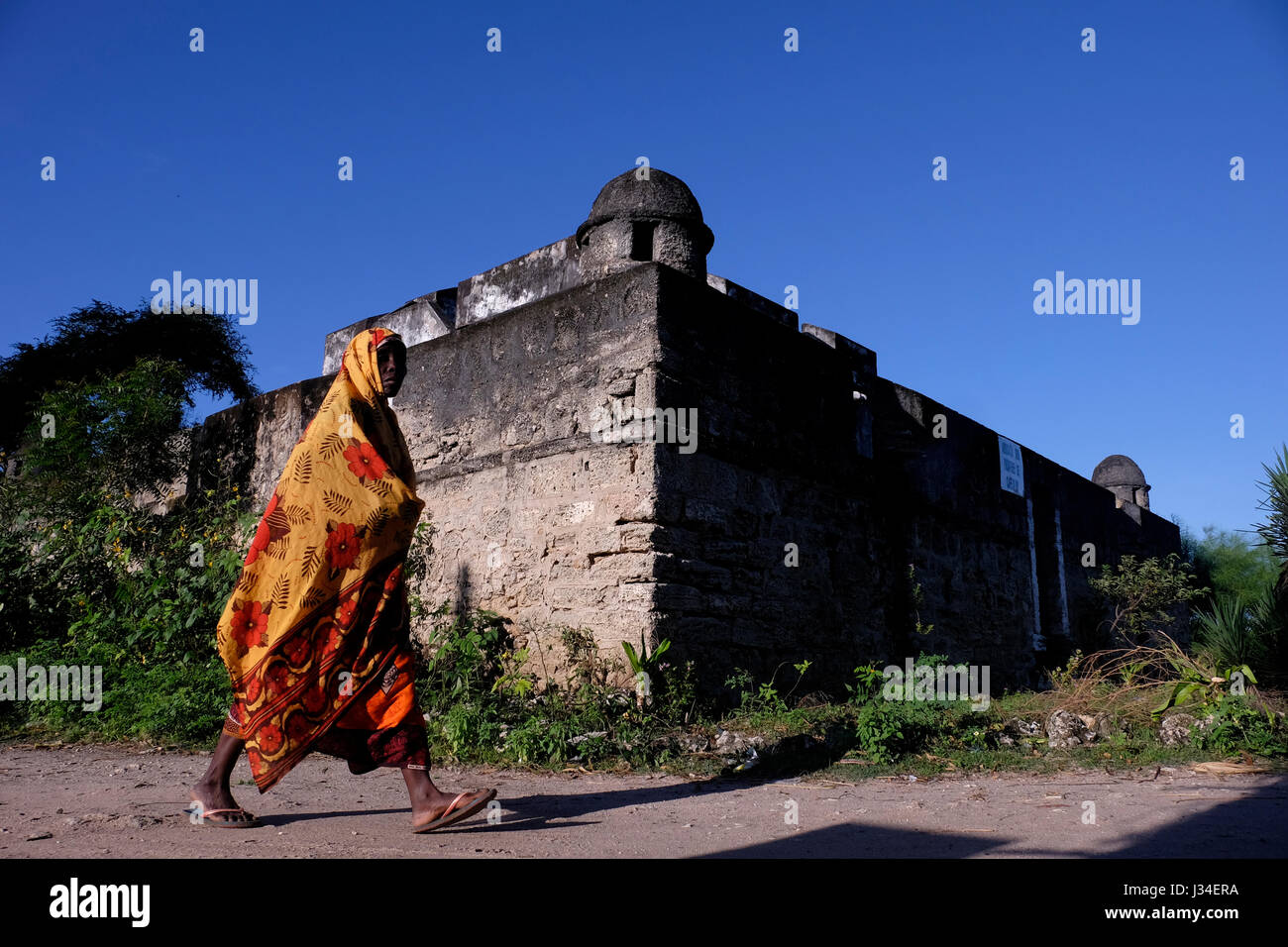 Une femme Mwani passe devant le fort de Fortim de Santo Antonio, l'un des trois forts portugais de l'île d'Ibo, l'une des îles de l'archipel de Quirimbas dans l'océan Indien au large du nord du Mozambique en Afrique Banque D'Images