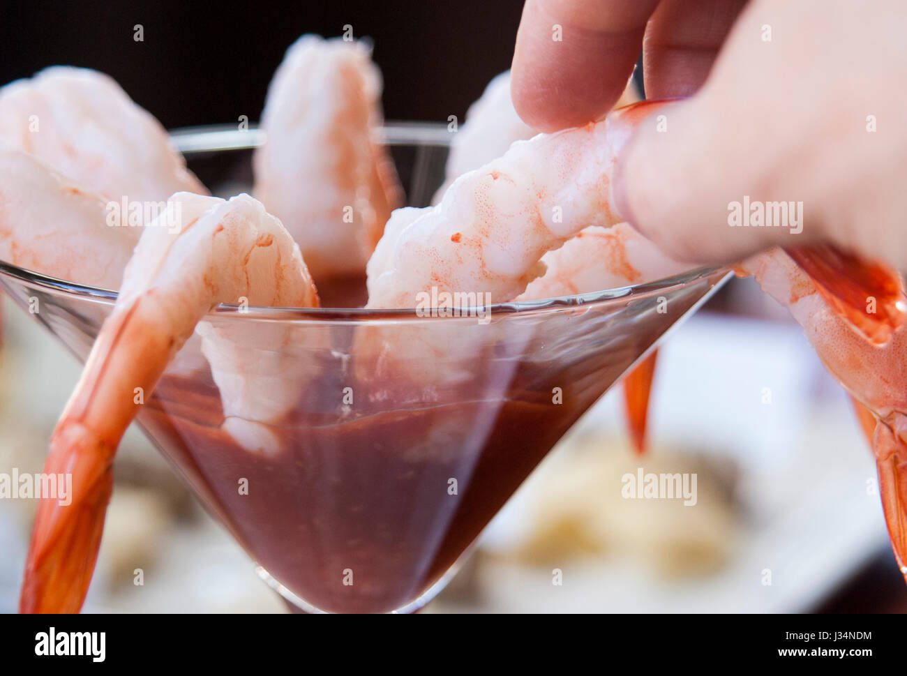 Un gros plan d'une main prendre un cocktail de crevettes dans un restaurant Banque D'Images