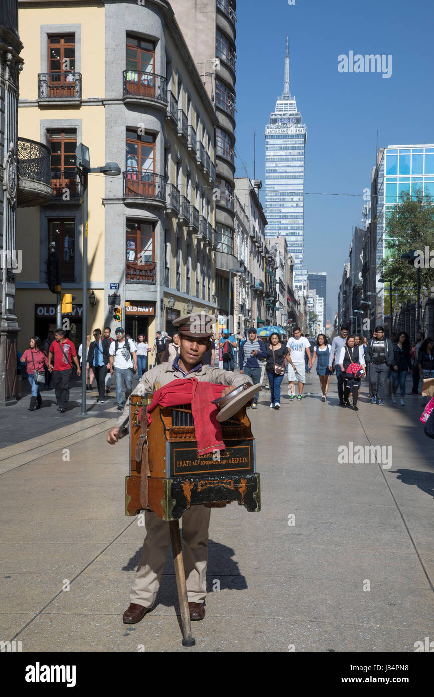La ville de Mexico, Mexique - 22 Avril 2017 : Orgue de Barbarie tient son chapeau pour les dons sur l'Avenue Francisco Madero dans le quartier historique. La Torre Latinoam Banque D'Images