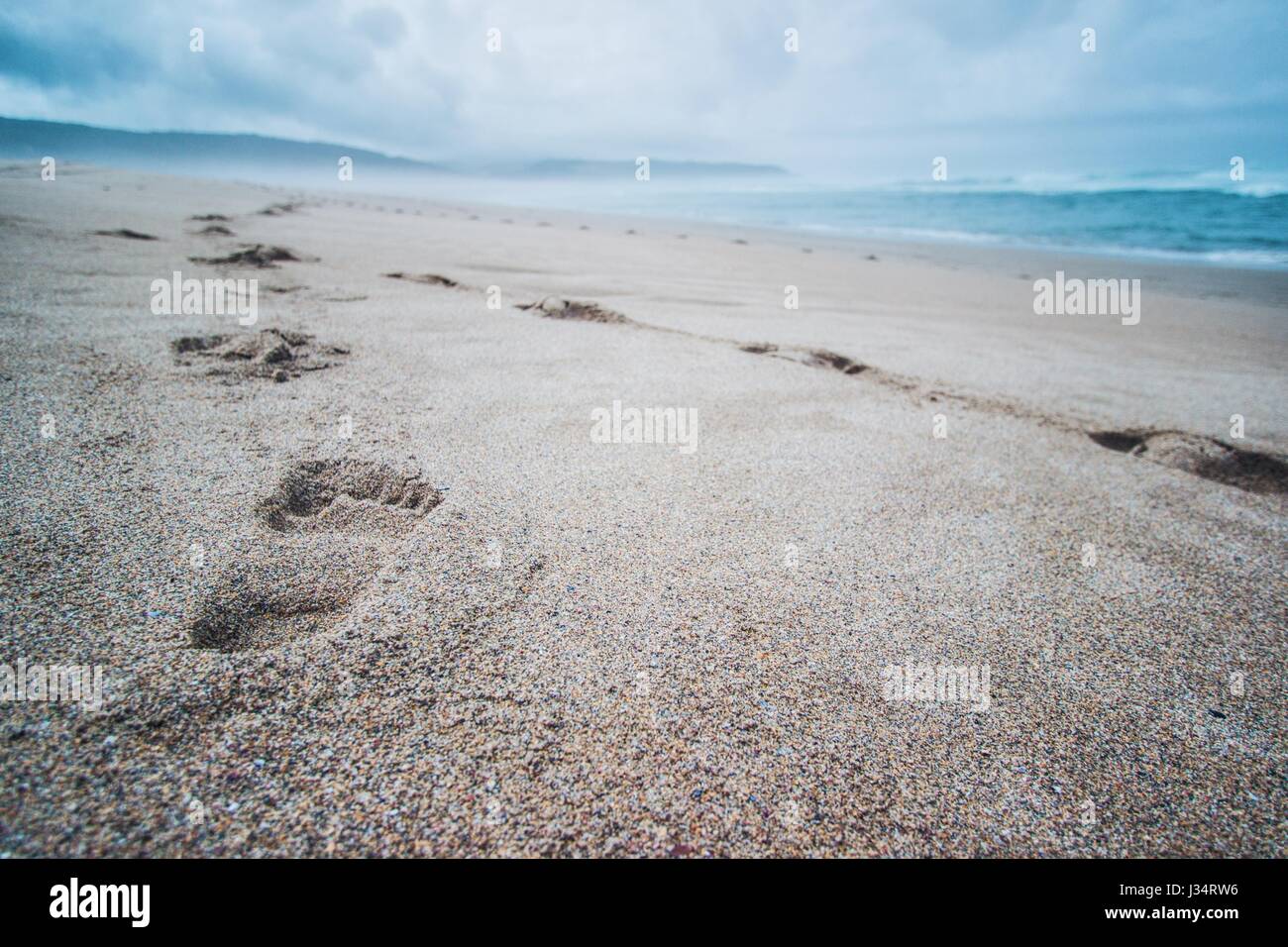 Empreintes laissées dans le sable d'une plage de la Galice, l'Espagne, dans une journée d'été brumeux Banque D'Images