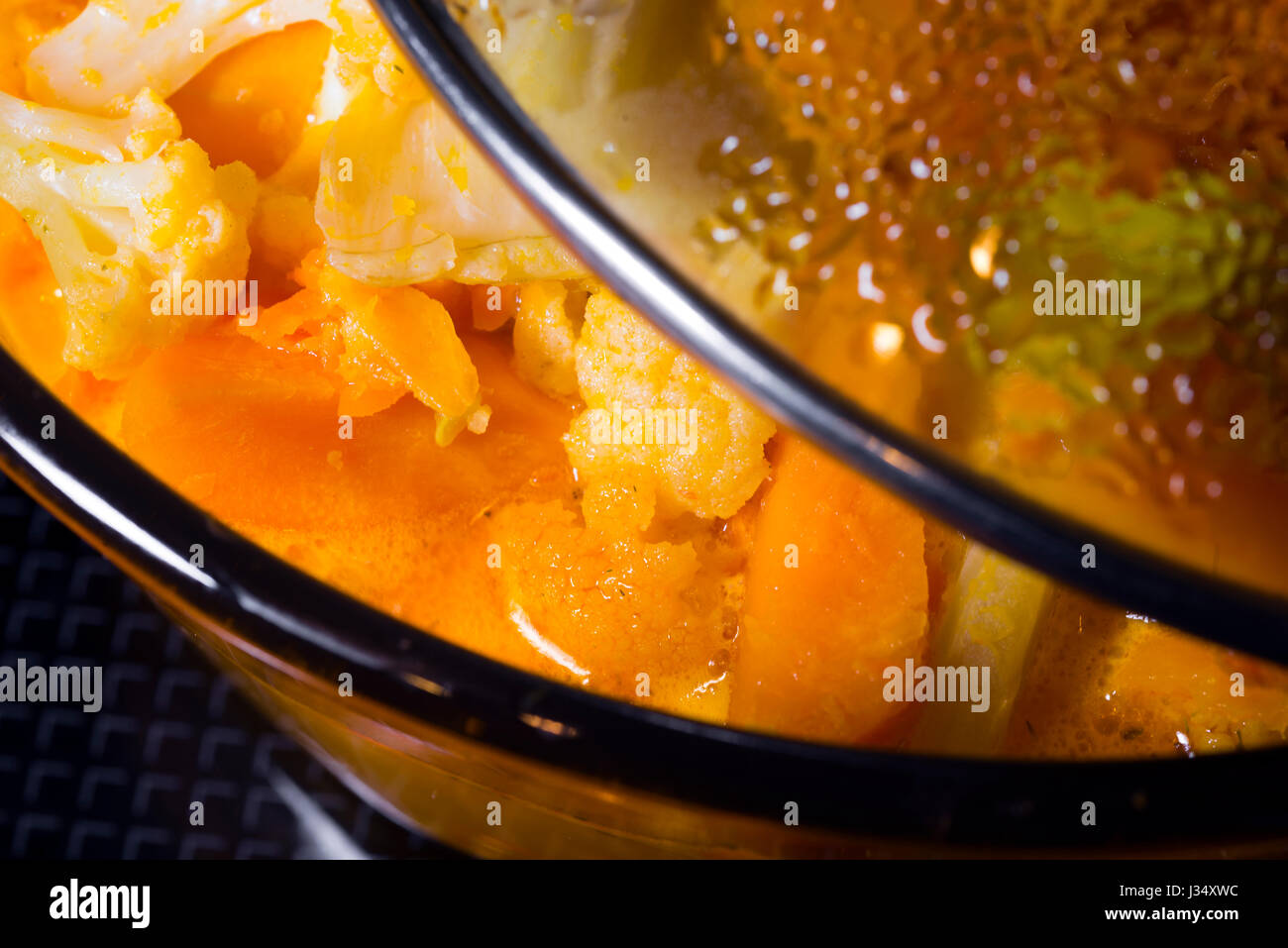 Casserole avec couvercle en verre dans lequel ajar citrouille cuite de soupe aux légumes avec les tranches de légumes. Ensemble de légumes - c'est une option de budget bon marché de d Banque D'Images