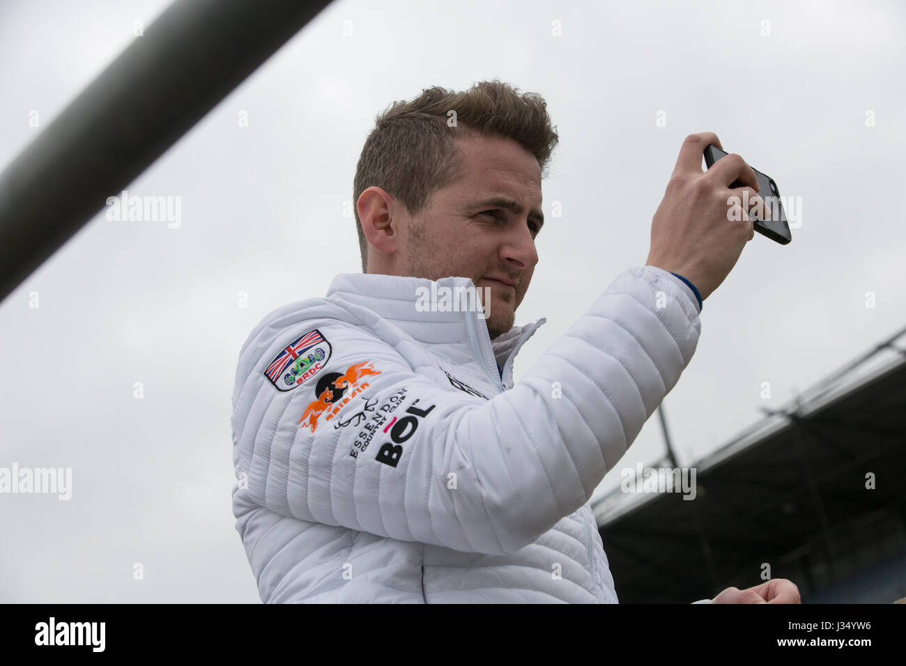 Sam Tordoff prenant une vidéo sur son téléphone des voitures de course at Rockingham Speedway durant British GT Banque D'Images