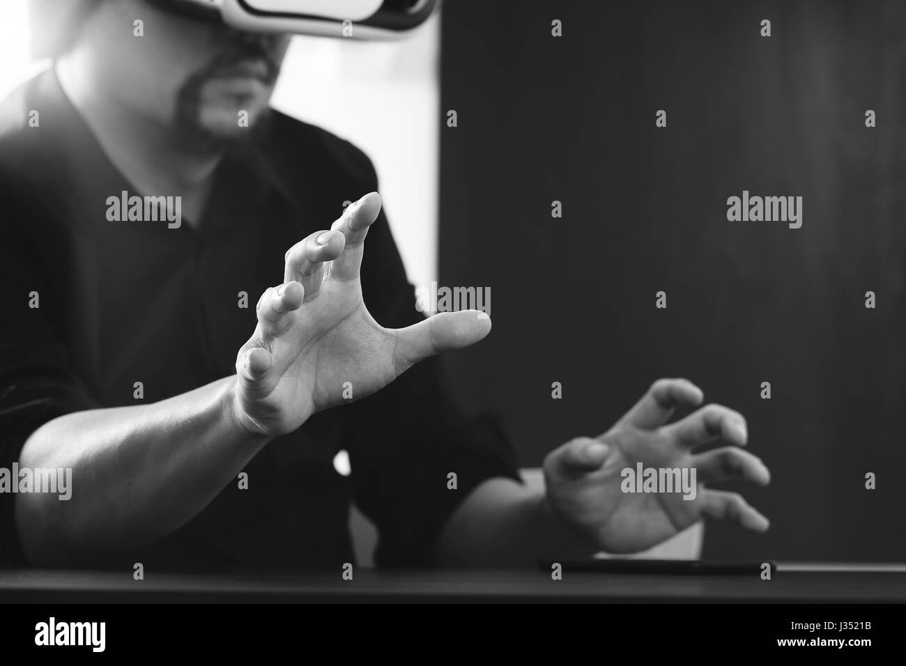 Businessman wearing lunettes de réalité virtuelle dans un bureau moderne avec l'aide du Smartphone avec casque VR noir et blanc Banque D'Images