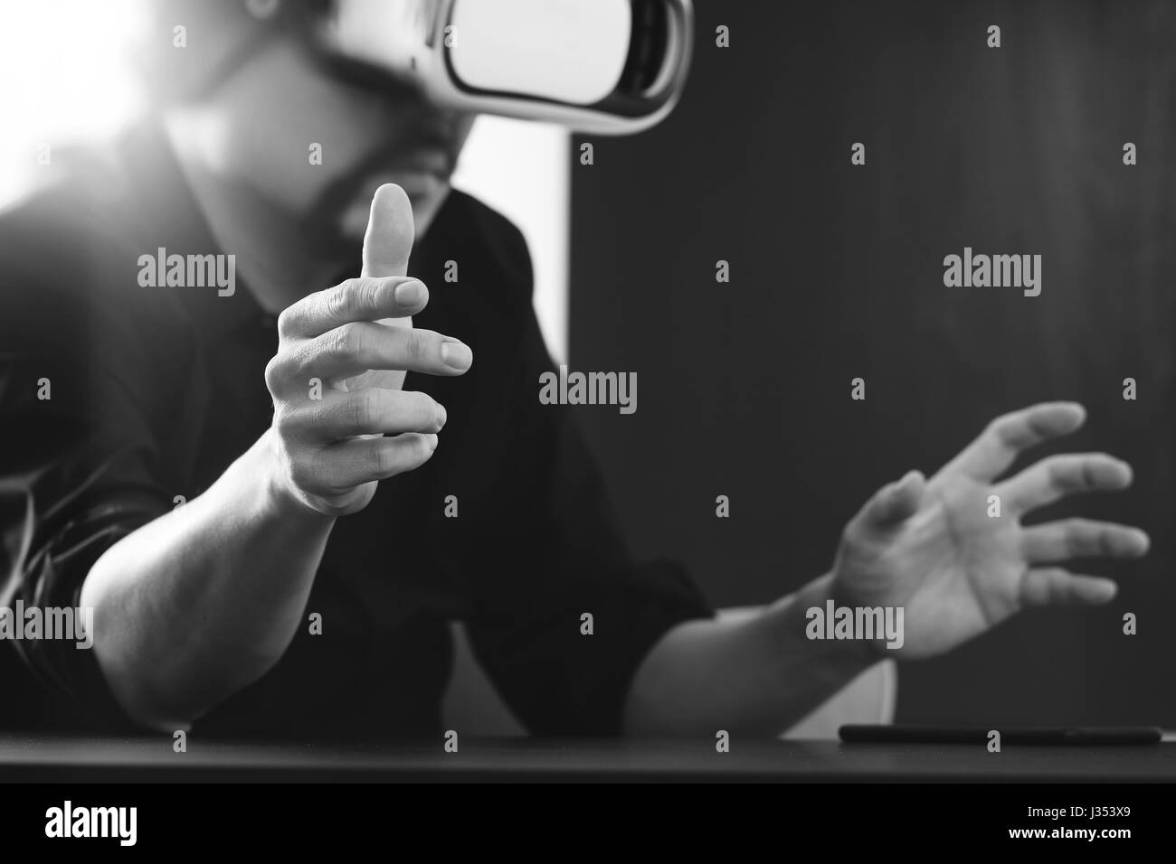 Businessman wearing lunettes de réalité virtuelle dans un bureau moderne avec l'aide du Smartphone avec casque VR noir et blanc Banque D'Images