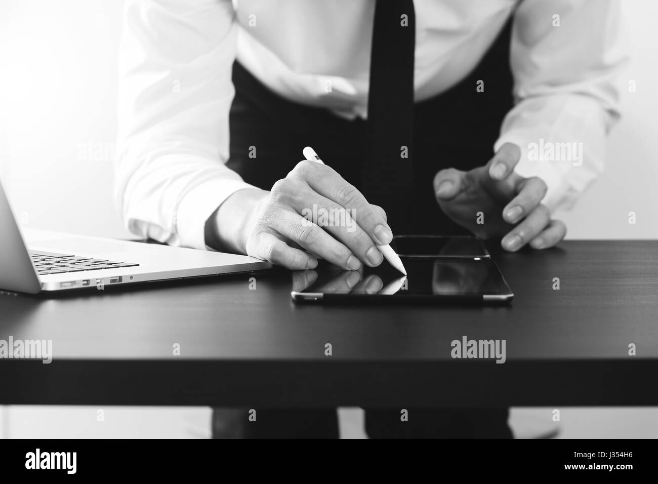 Close up of young avec smart phone et digital tablet ordinateur sur un bureau en bois moderne en noir et blanc, Banque D'Images