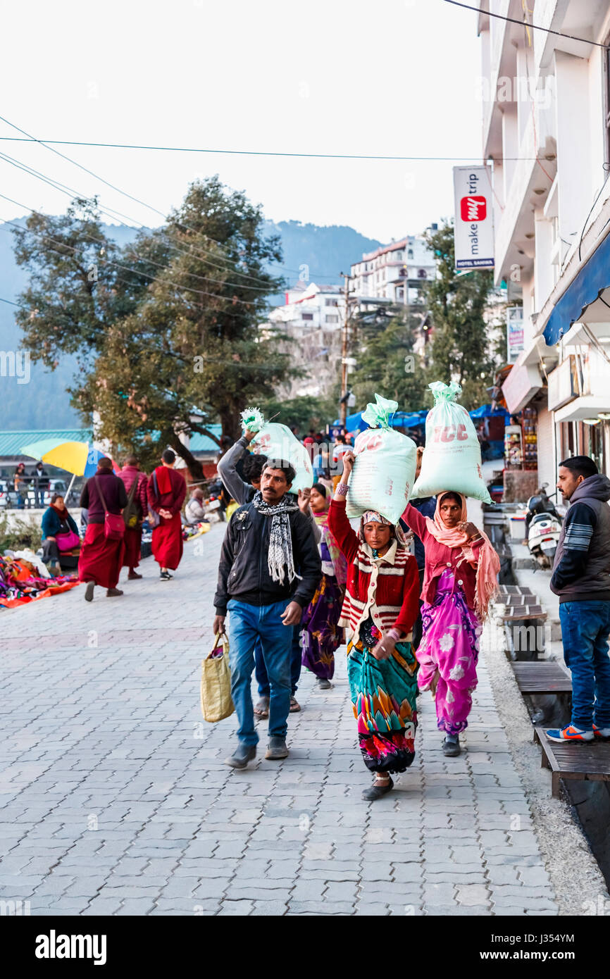Le mode de vie des Indiens : les femmes locales de transporter de grosses charges lourdes dans des sacs sur leurs têtes dans la rue en McLeodGanj, Dharamshala, Himachal Pradesh, Inde Banque D'Images