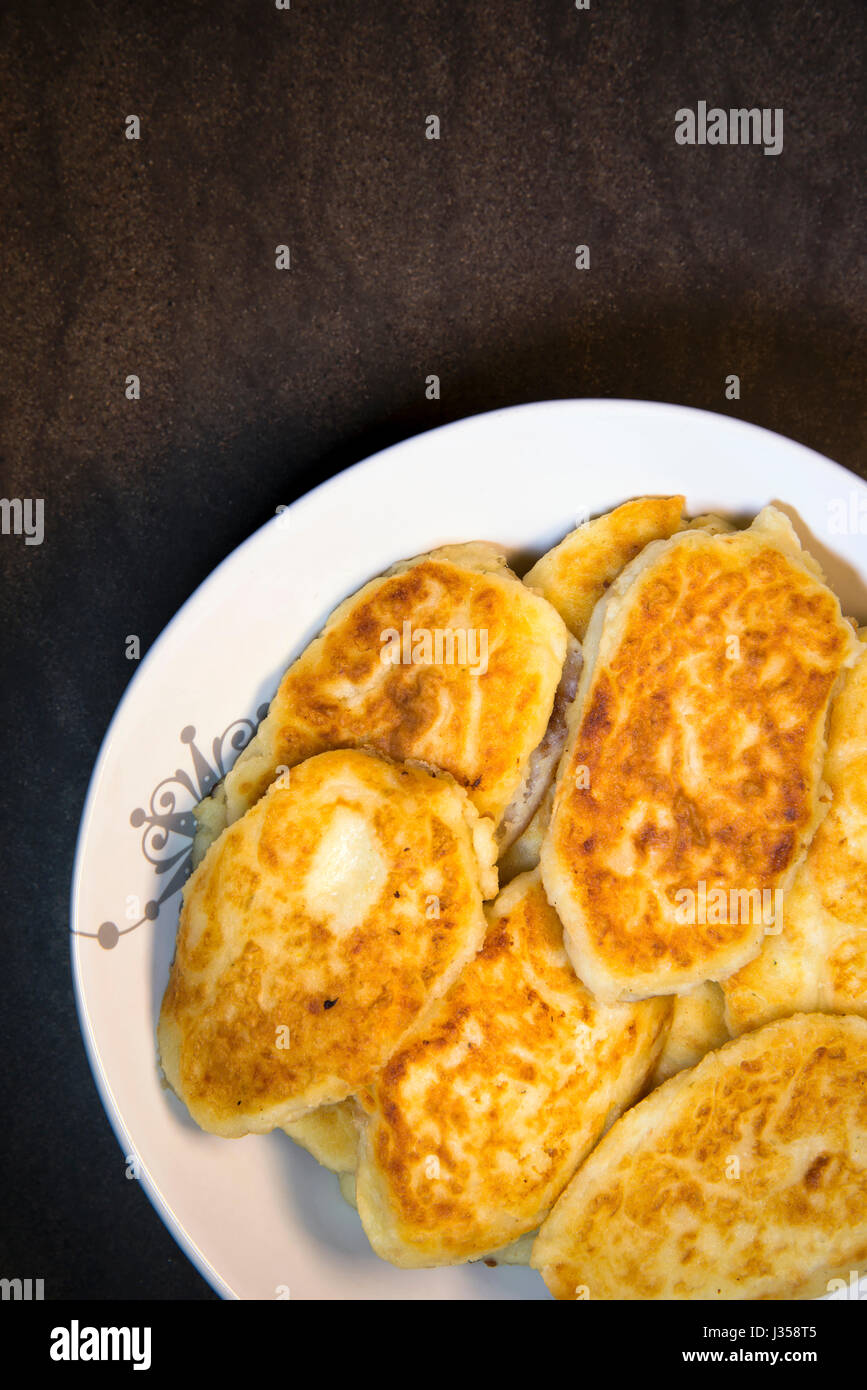 Les galettes de pommes de terre frites ruddy de nutriments sous forme de pâtisseries disposés sur une assiette et prêt à manger à la table de dîner de famille. Il fait référence à une main Banque D'Images