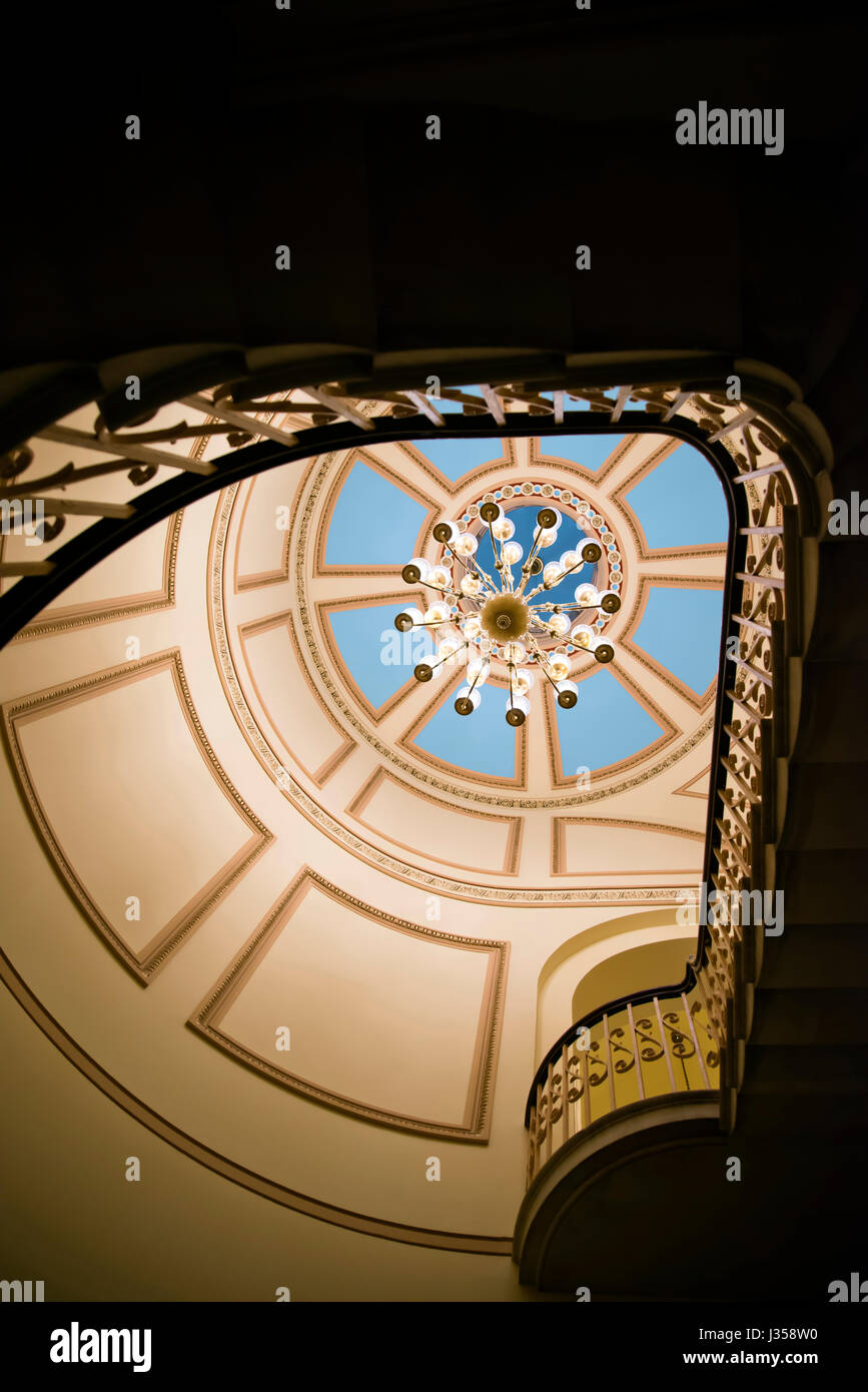 Lustre en cristal lampes multiples dans l'escalier intérieur avec plafond à motifs peints de couleur décoré de peintures géométriques ajourés, encadrées par Banque D'Images