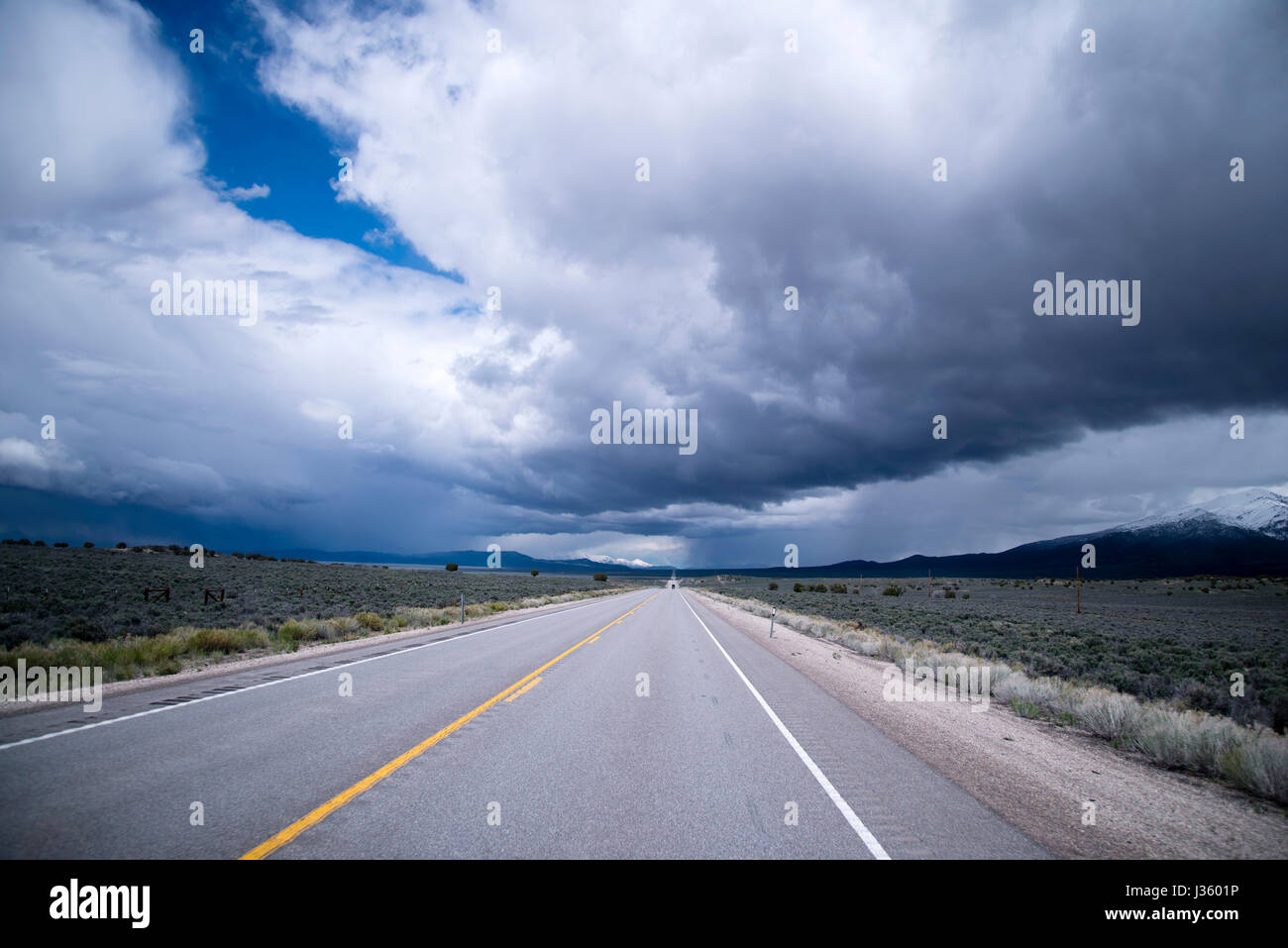 Ciel d'orage avec de gros nuages et l'interminable route qui passe entre les étendues de prairie Nevada répondre à l'horizon, de la création d'une seule photo terres steppiques Banque D'Images