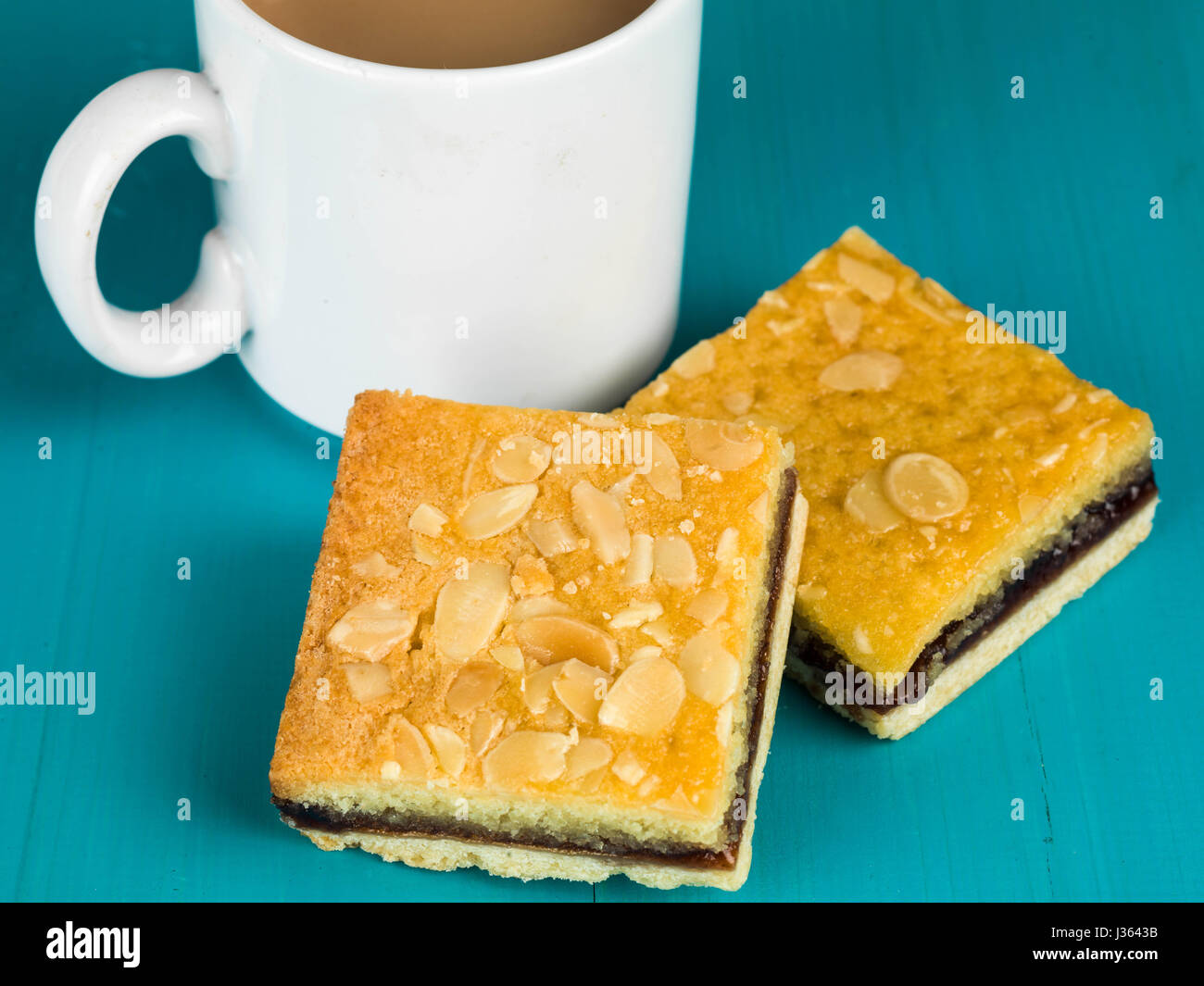 Tartelettes bakewell cerise avec une tasse ou tasse de thé ou de café sur un fond bleu Banque D'Images