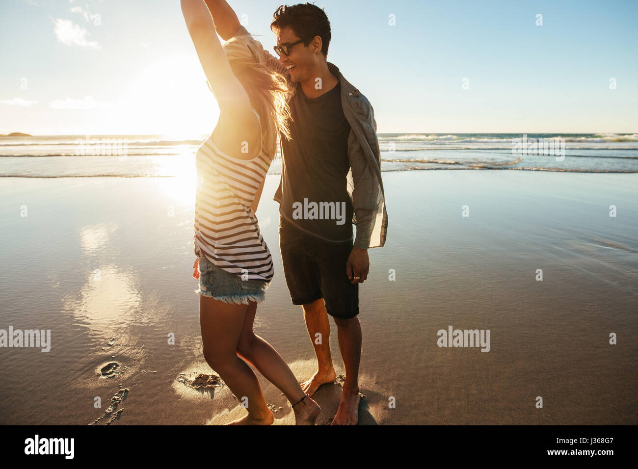 Coup de jeune couple aimant danser sur la plage un jour d'été. Jeune homme et femme dansant sur la mer. Banque D'Images