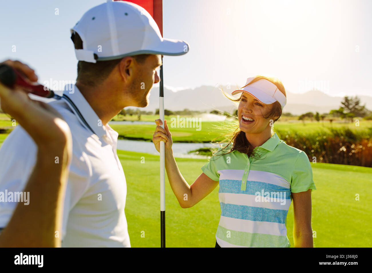 Couple de golf sur le green de golf. Avec mâle et femelle stick golf holding drapeau. Banque D'Images