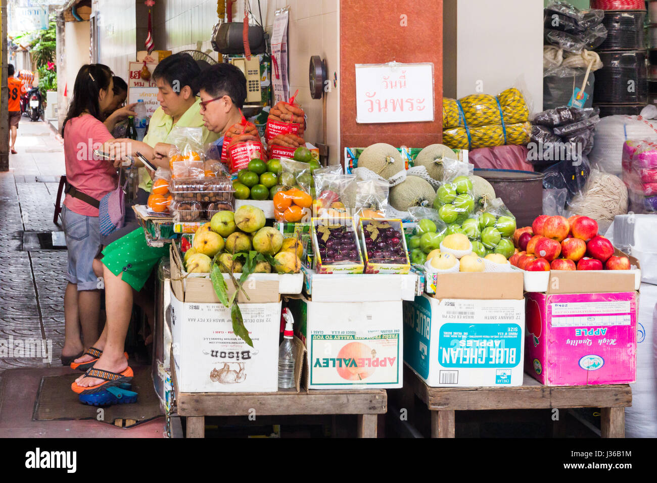 Les vendeurs de téléphones portables par les femmes sur leur étal de fruits de rue dans le quartier chinois, Bangkok, Thaïlande Banque D'Images