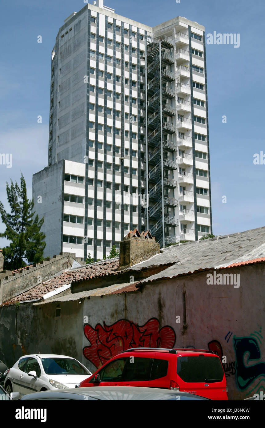 Bloc de bureau laid surplombe un petit groupe de 20 cottages construits accidents c1890, maintenant abandonné et menacé de démolition, dans Campodile, Lisbonne. Banque D'Images