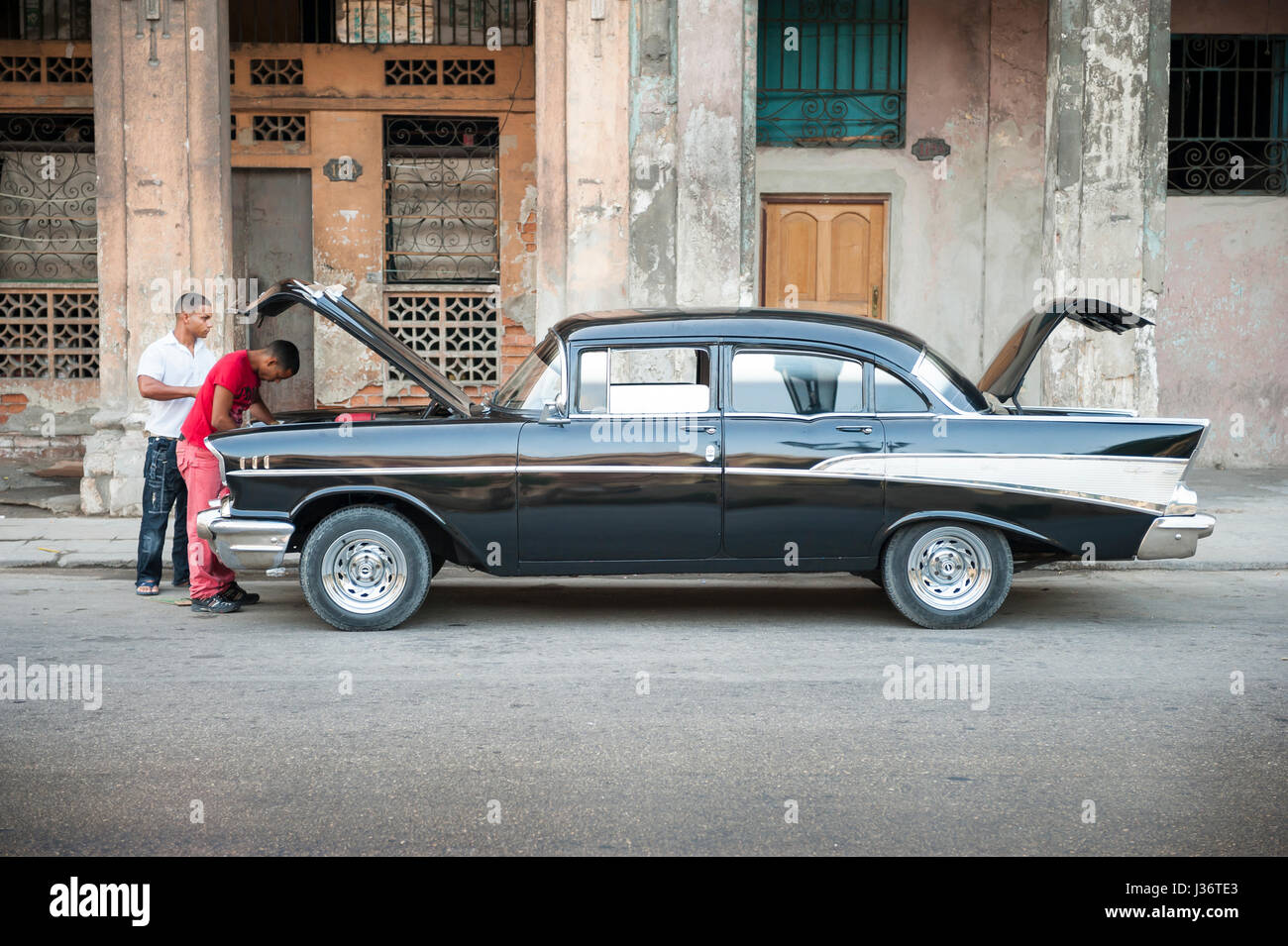 - La Havane, juin 2011 : hommes cubains d'oeil dans le moteur d'une vieille voiture américaine en tant qu'ils effectuent l'entretien de la rue. Banque D'Images