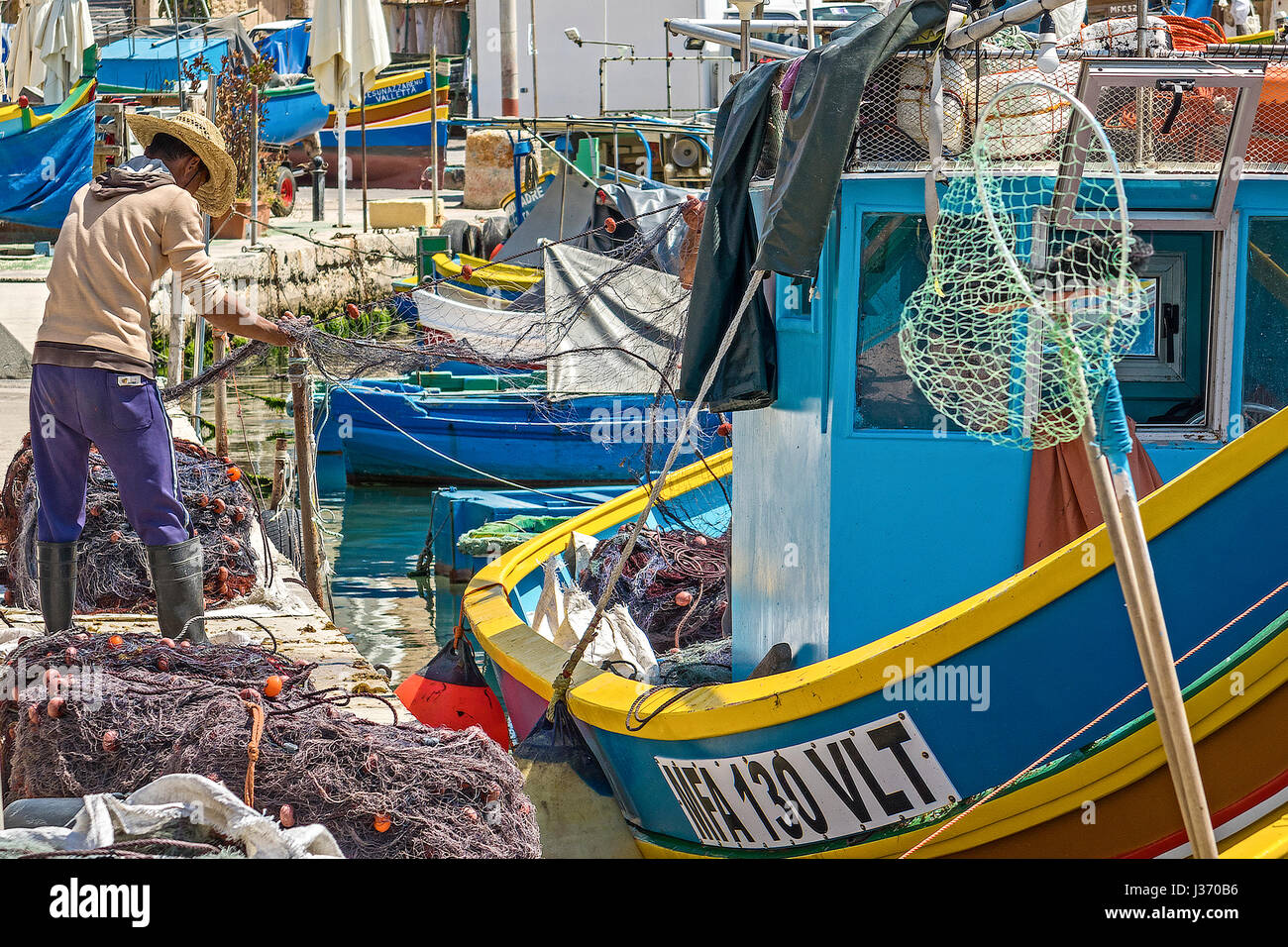 Les pêcheurs travaillant sur leurs filets, Village de Marsaxlokk, Malte Banque D'Images