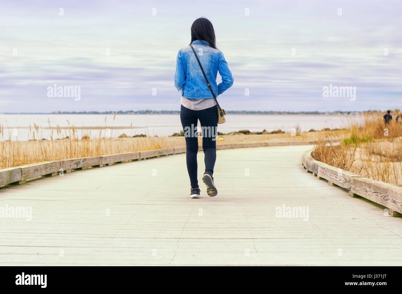 Une femme chinoise sur une promenade à pied entre le parc d'état de Silver Sands et Walnut Beach Milford dans le Connecticut sur l'image. Banque D'Images