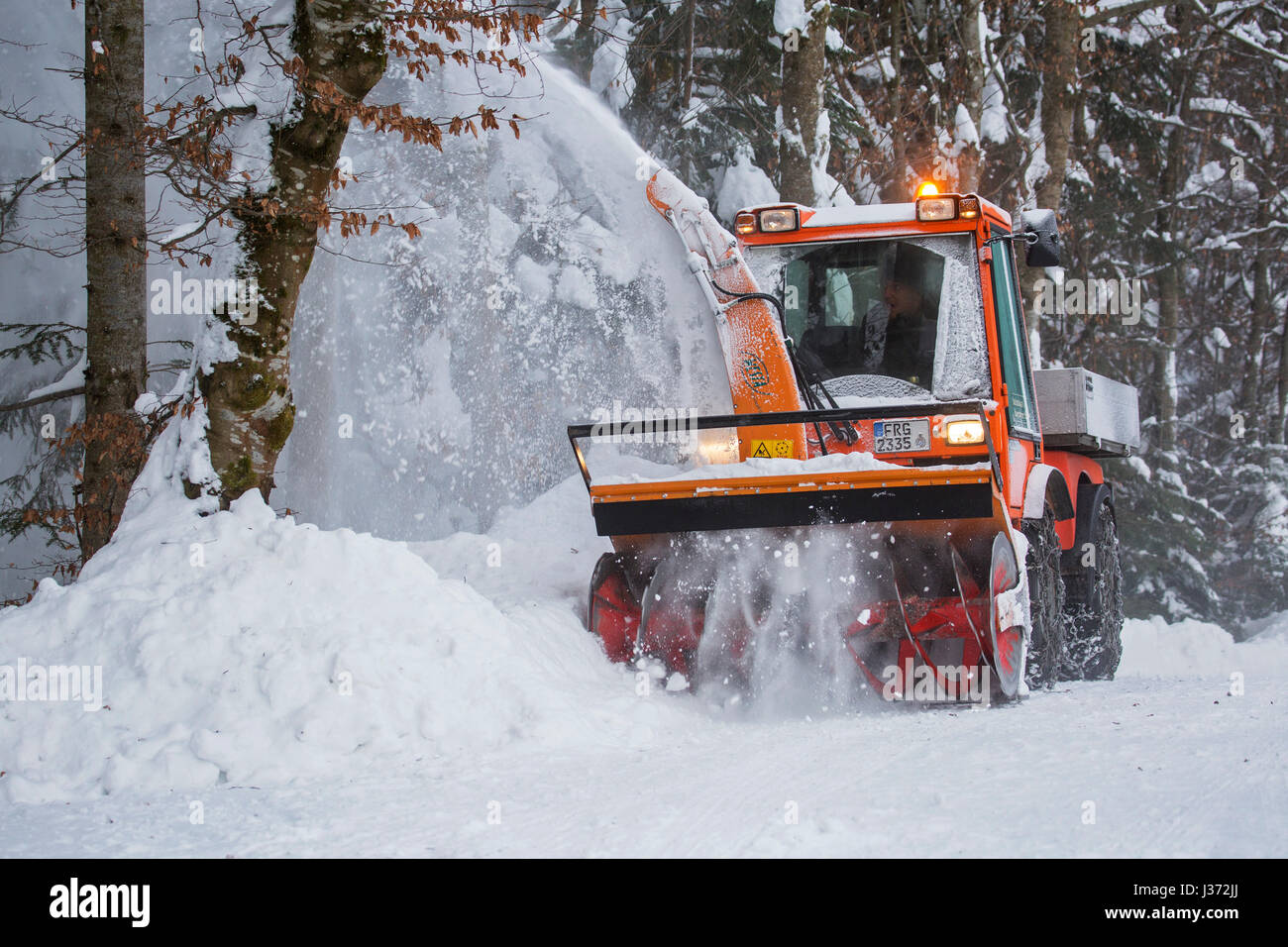C9700H tracteur souffleur à neige municipale avec de la neige à partir de la route en forêt après les fortes chutes de neige en hiver Banque D'Images