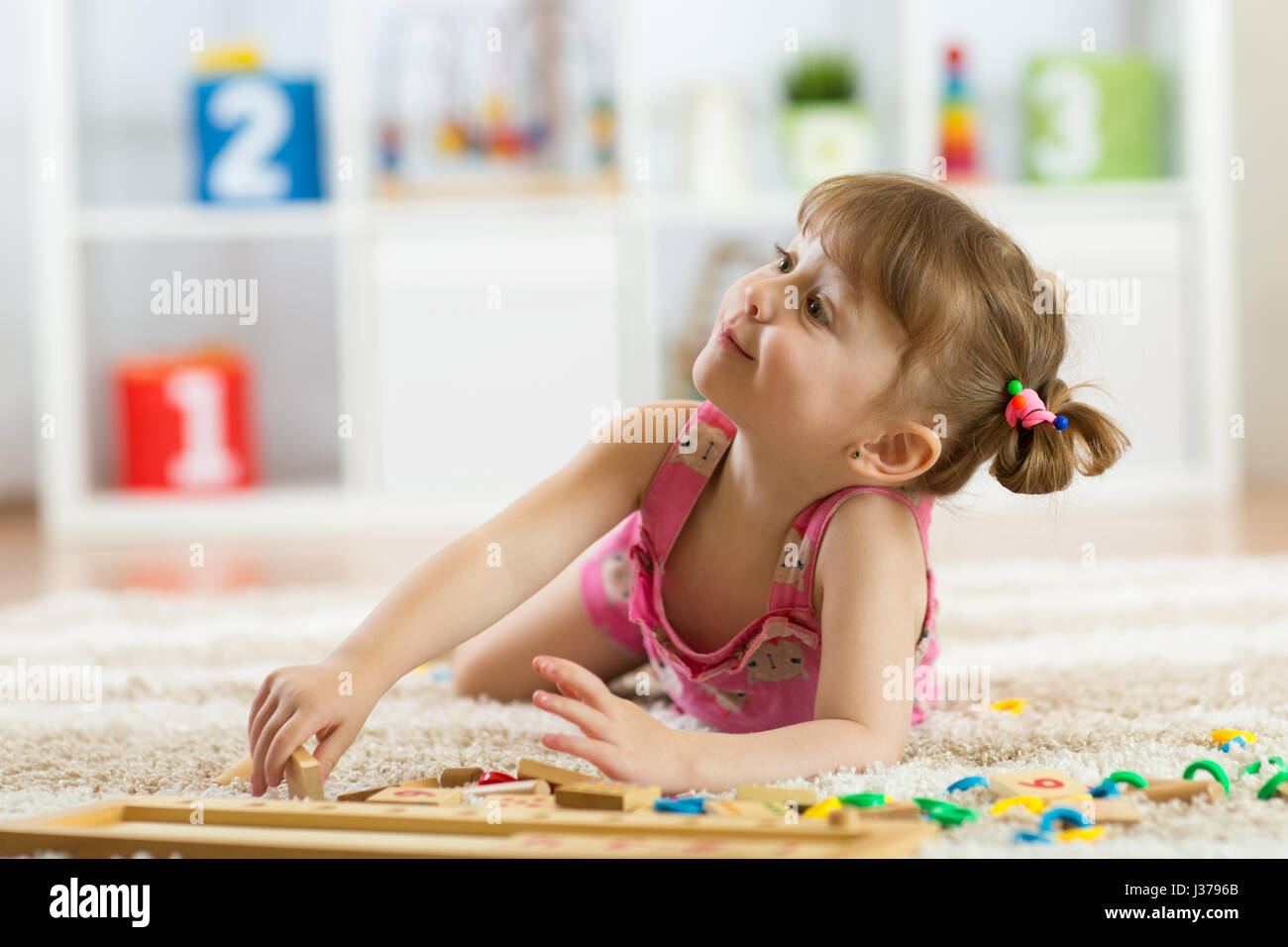 Cute little girl Playing with jouet éducatif blocs dans un jardin ensoleillé chambre. Les enfants jouent. Les enfants à la garderie. Banque D'Images