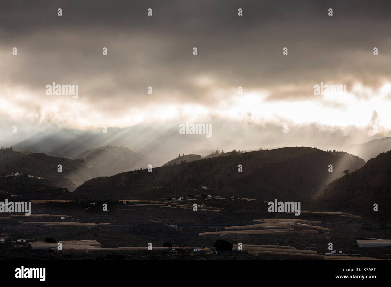 Les rayons du soleil brillent à travers les nuages de tempête à l'aube sur les contreforts et les montagnes en Guia de Isora, sur l'ouest de Tenerife, Canaries, Espagne Banque D'Images