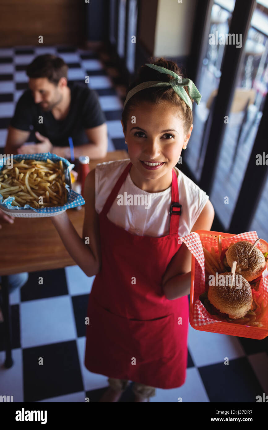 Portrait of a waitress holding burger et frites dans le bac au restaurant Banque D'Images