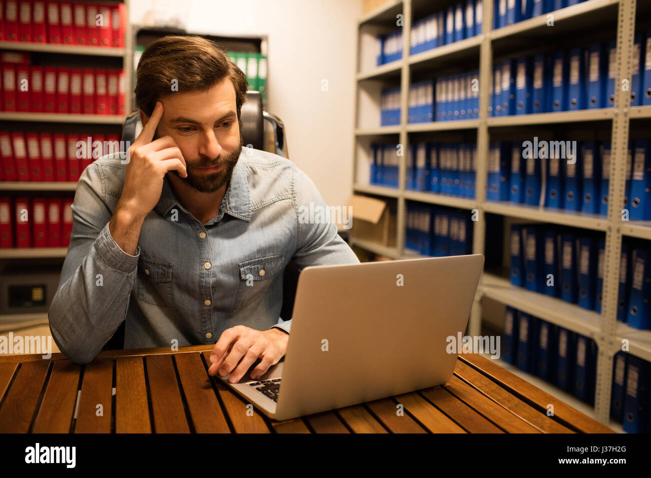Thoughtful businessman using laptop in stockage sur le lieu de travail Banque D'Images