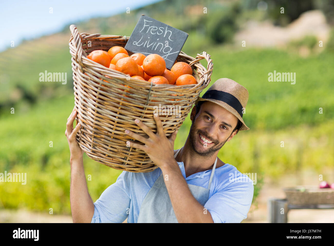 Portrait of smiling farmer l'exercice par les oranges fraîches dans un récipient au marché à la ferme à vendre Banque D'Images