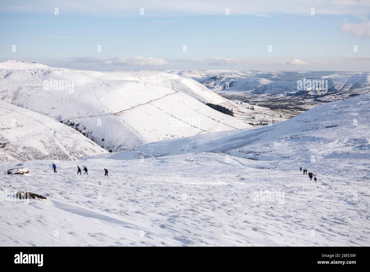 Un groupe de randonneurs marchant Kinder Scout dans l'hiver avec Edale valley dans la distance. Peak District, UK Banque D'Images