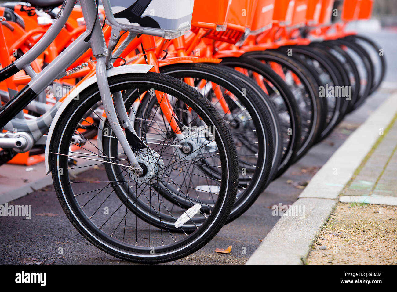 Vélos orange avec des paniers à l'avant et roues polies pour les utiliser et bordée d'un séjour vélo gris pas symboliques susceptibles d'autres se Banque D'Images